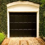 ivy-covered-growing-garage-black-door-brick