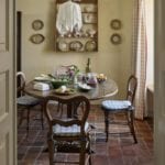 Imogen limewashed walls apricot colour oak vendange table surrounded by nineteenth-century English chairs cushions Colefax and Fowler fabric check by Pierre Frey curtains plates on the wall