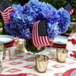 danielle-rollins-fourth-of-july-tablescape-blue-hydrangea-centerpiece-american-flags-ikat-mercury-glass-caraf