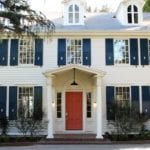 Lovely colonial home with coral front door painted Benjamin Moore Golden Gate and navy blue shutters painted Benjamin Moore In the Midnight Hour