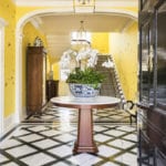 yellow-gracie-wallpaper-butterflies-entrance-hall-entry-stairs-staircase-black-white-marble-floors-lacquered-door-round-table