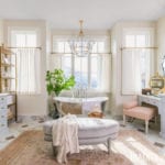 rachel-parcell-master-bathroom-mirrored-bath-tub-vanity-sheer-white-curtains-blue-painted-cabinets-persian-rug-ottoman