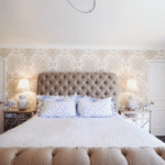 quadrille-Sigourney-wallpaper-bedroom-taupe-beige-camel-tufted-headboard-donghia-d-porthault-linens-mirrored-nightstands